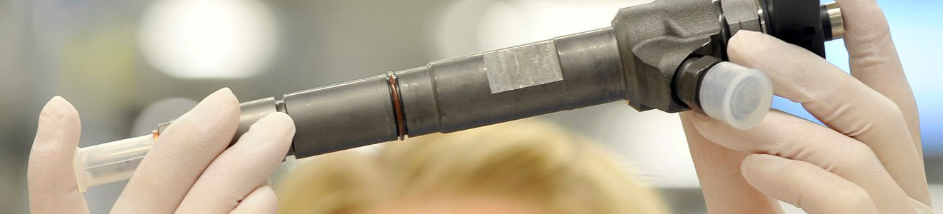 A common rail injector being inspected by a technician wearing clean room gloves